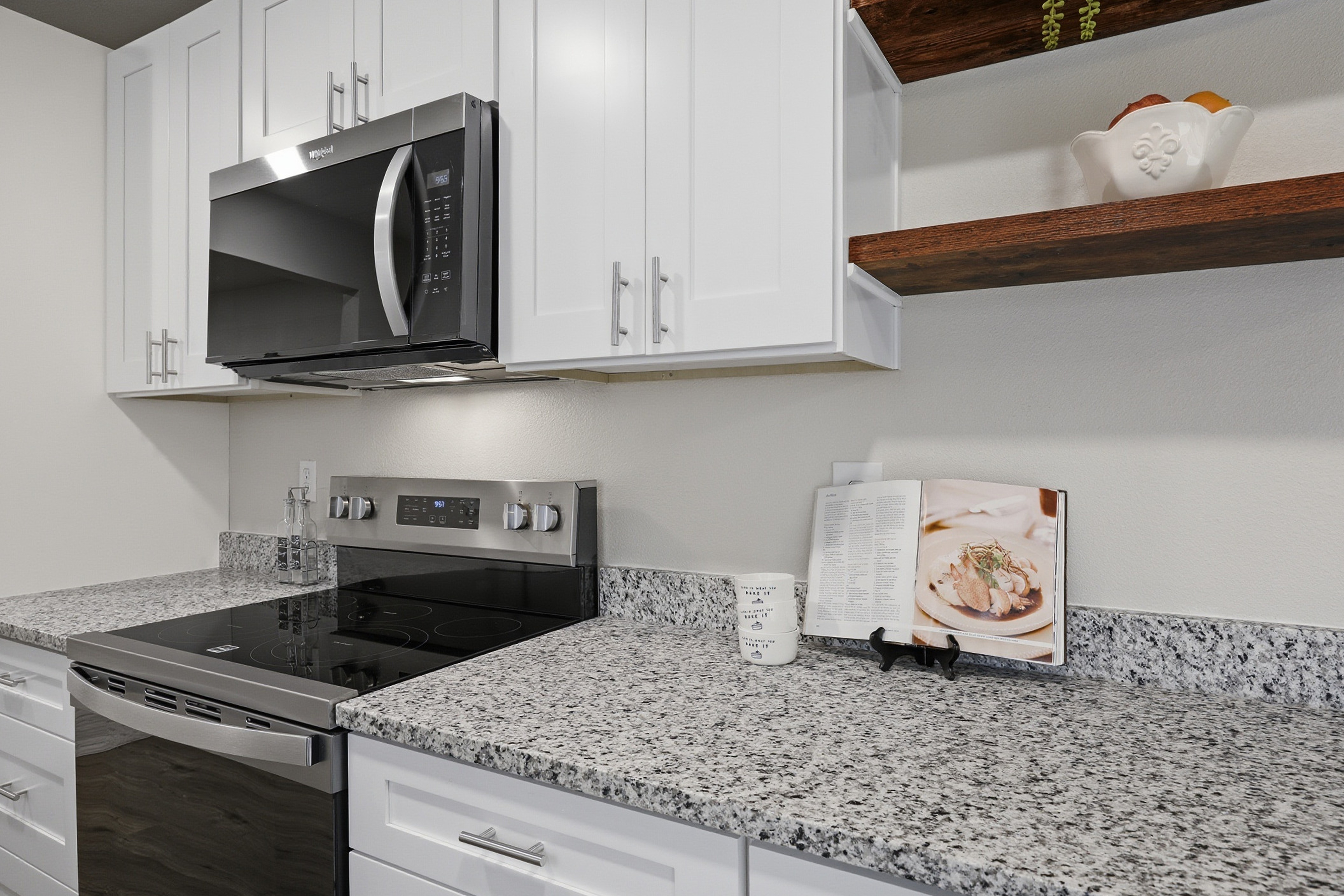 Kitchen appliance wall with stainless range, microwave, and granite counter